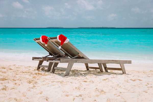 Christmas on beach -chair lounges with Santa hats at sea