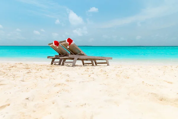 Navidad en la playa-silla salones con sombreros de Santa en el mar — Foto de Stock