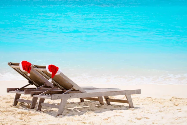 Christmas on beach-chair lounges with Santa hats at sea — стоковое фото