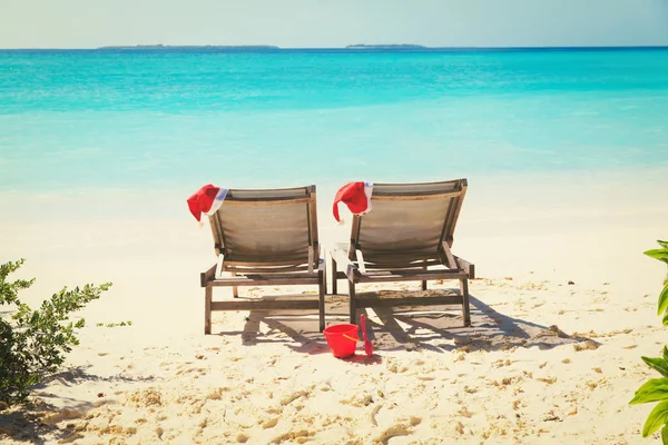 Christmas on beach-chair lounges with Santa hats at sea — стоковое фото