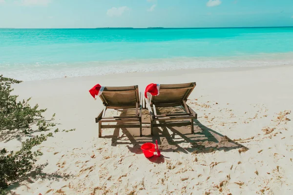 Navidad en la playa-silla salones con sombreros de Santa en el mar —  Fotos de Stock