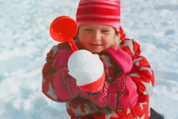 Niña haciendo bola de nieve en la naturaleza de invierno — Foto de Stock