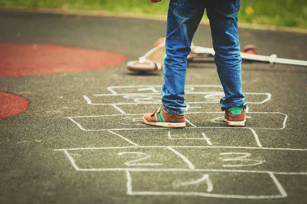 Pequeno menino jogar hopscotch no playground — Fotografia de Stock