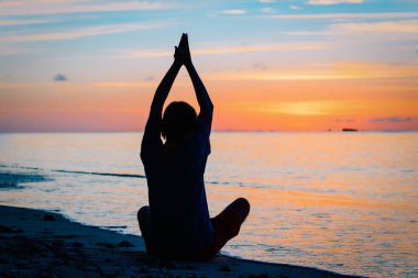Gün batımında yoga yaparken genç adam silüeti