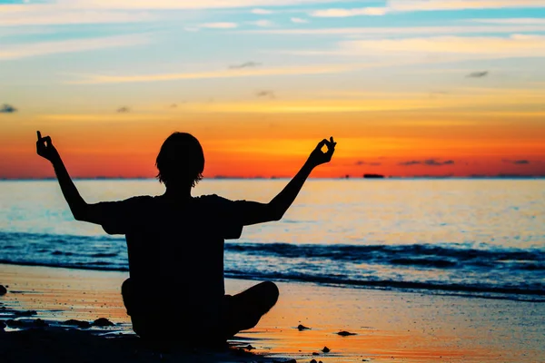 Silhouette de jeune homme faisant du yoga au coucher du soleil — Photo