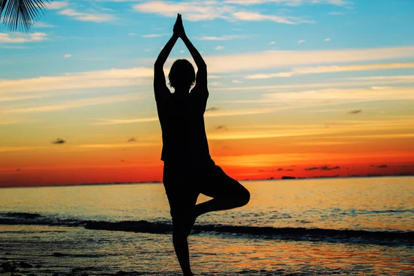 Gün batımında yoga yaparken genç adam silüeti — Stok fotoğraf