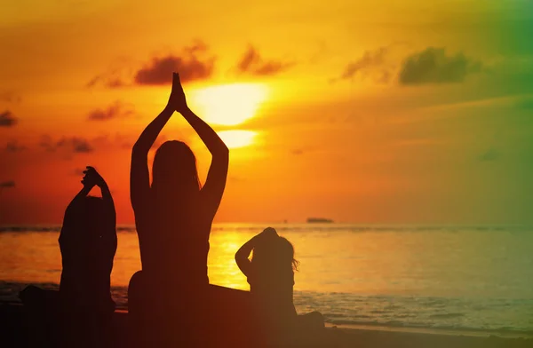 Silueta de la madre y los niños haciendo yoga al atardecer — Foto de Stock