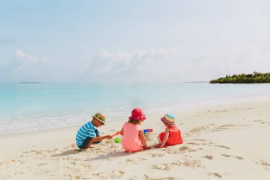 küçük kız ve erkek sahilde kum ile oynamak