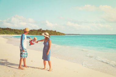 Aile ile tropik sahilde oynarken küçük bebek