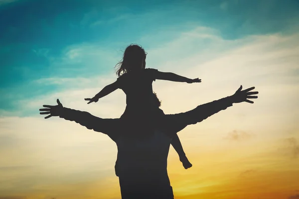 Батько і маленька дочка грають на заході сонця неба — стокове фото