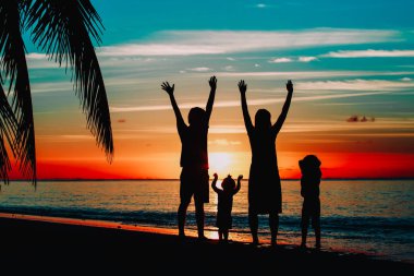 Çocuklu mutlu bir aile gün batımı kumsalında oynuyor.