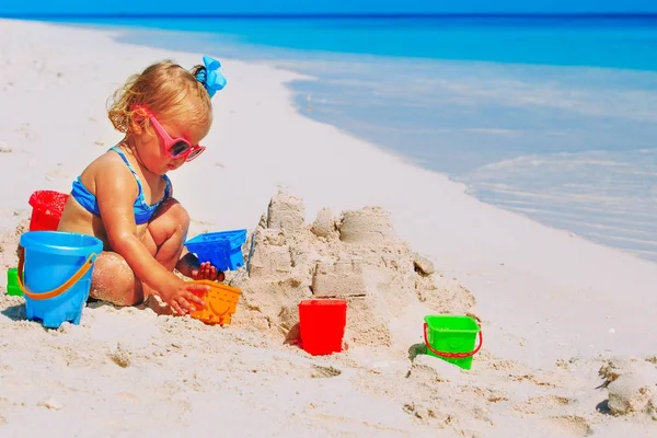Niedliche kleine Mädchen spielen mit Sand am Strand — Stockfoto