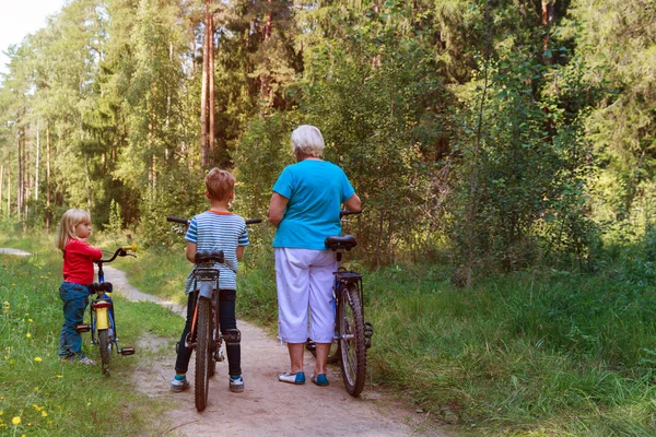 Senior activo con nietos montando bicicletas en la naturaleza —  Fotos de Stock