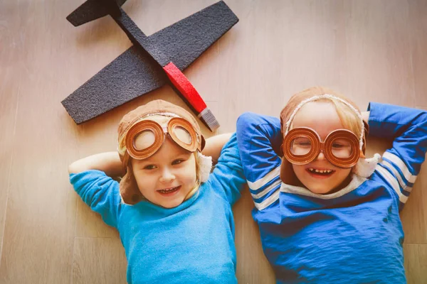 Glada barn med hjälm och glasögon leka med leksak plan — Stockfoto