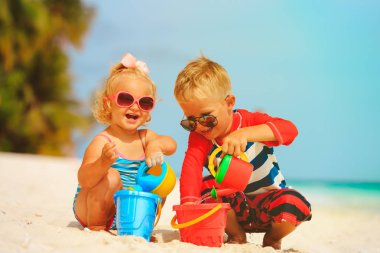 küçük erkek ve kız sahilde su ile oynamak