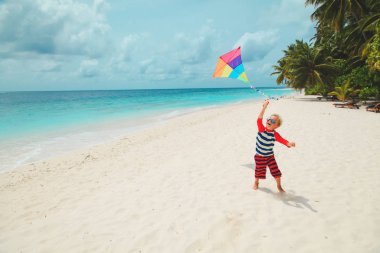 Tropik sahilde uçurtma uçuran mutlu küçük çocuk