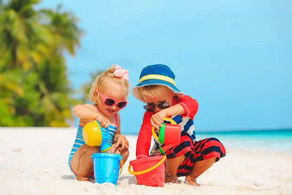 Kleine jongen en meisje spelen met water op het strand — Stockfoto