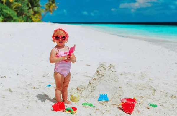 Söt liten flicka spela med sand, bygga slott på stranden — Stockfoto