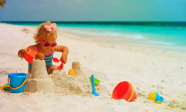 Cute little girl play with sand, building castle on beach — стоковое фото