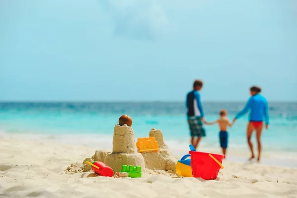 Vacaciones de playa familiar- castillo de arena y familia en la costa del mar —  Fotos de Stock