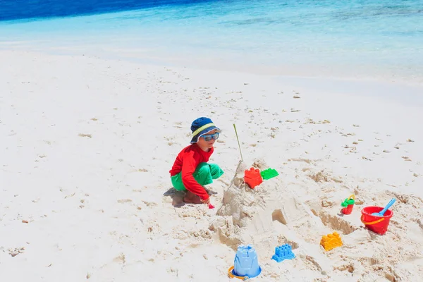 Piccolo ragazzo costruzione castello di sabbia sulla spiaggia — Foto Stock