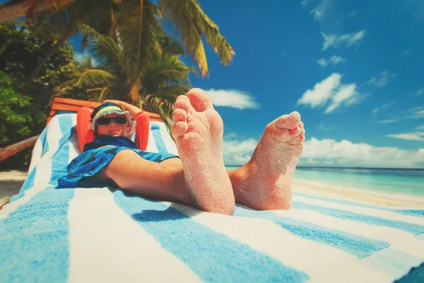 little boy relax on tropical beach, focus on feet
