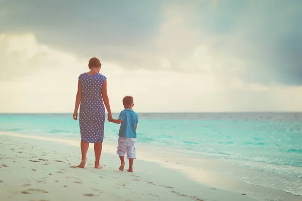 Mère et petit fils marchant sur la plage du coucher du soleil — Photo