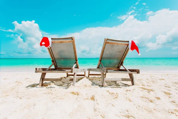 Christmas on beach-chair lounges with Santa hats at sea — стоковое фото