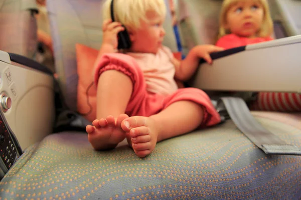 Lindo pequeño bebé con hermana viajar en avión ver la televisión en vuelo — Foto de Stock