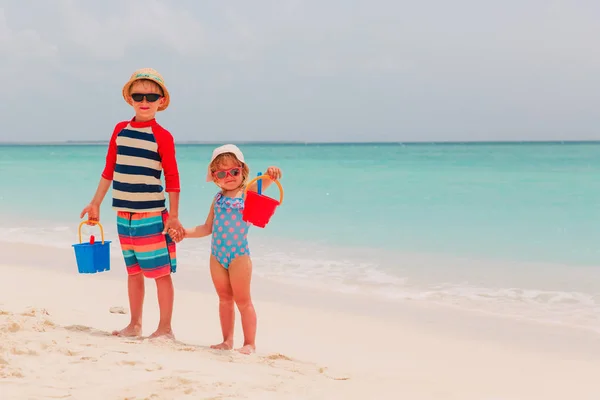 Kleine jongen en meisje spelen met water en zand op strand — Stockfoto