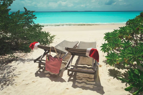 ビーチのクリスマス-海でサンタの帽子が付いているラウンジの椅子 — ストック写真