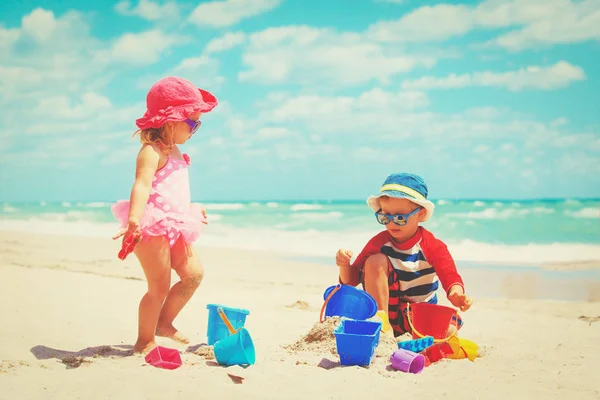 Küçük oğlan ve kız kumsalda kumla oynuyorlar. — Stok fotoğraf
