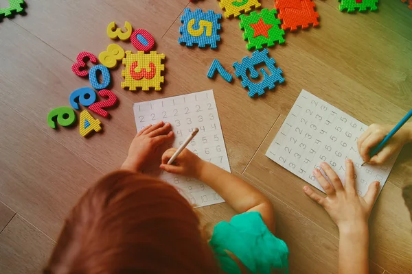 Kleine jongen en meisje leren om te schrijven en het berekenen van de getallen — Stockfoto