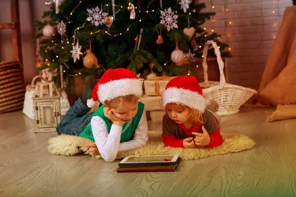 Τα παιδιά επιλέγουν χριστουγεννιάτικα δώρα σε αφής σε διακοσμημένο σαλόνι — Φωτογραφία Αρχείου