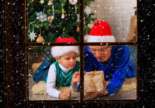 Πατέρας και γιος με δώρα στο Χριστουγεννιάτικο σαλόνι είδαν από ouside παράθυρο — Φωτογραφία Αρχείου