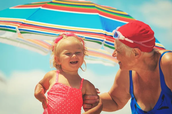 Счастливая бабушка с маленькой внучкой на пляже — стоковое фото