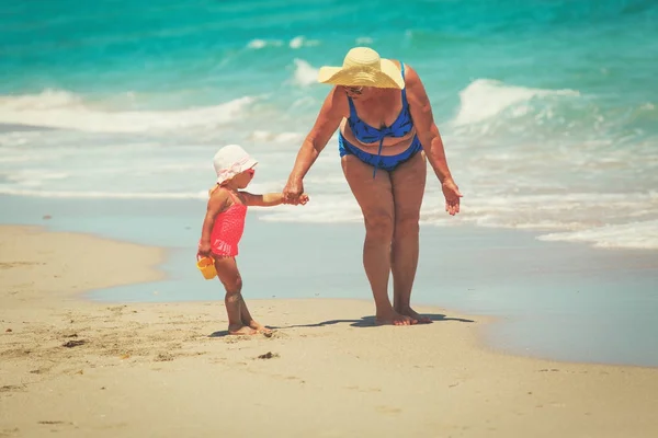Grandmother and little granddaughter go swim on beach — Stock Photo, Image