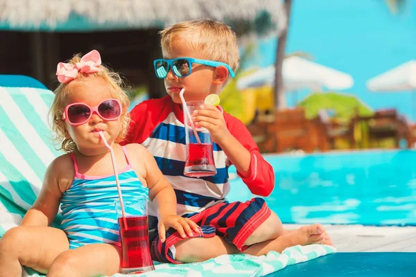 Menino e menina bebendo sucos na praia — Fotografia de Stock