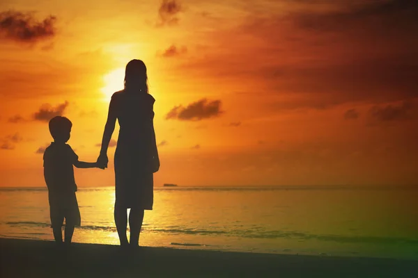 Moeder en zoon wandelen op zonsondergang strand — Stockfoto