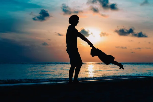 Pai e pequena filha silhuetas jogar ao pôr do sol — Fotografia de Stock