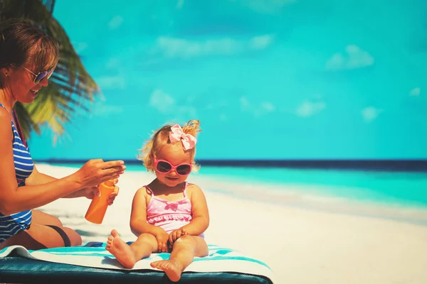 Äiti soveltamalla aurinkovoidetta pienelle tyttärelle — kuvapankkivalokuva