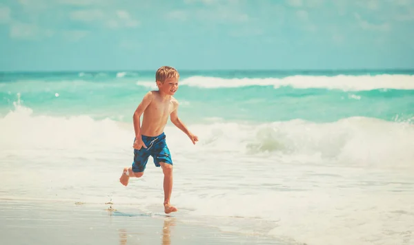 Kleine jongen spelen met water uitvoeren op strand — Stockfoto