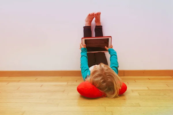 Kleines Mädchen schaut auf Touchpad, lernt zu Hause — Stockfoto