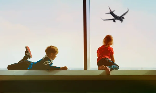 Дети смотрят на самолет в аэропорту, семейные поездки — стоковое фото