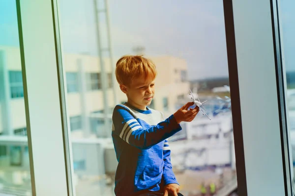 Chico jugando con juguete avión mientras espera en aeropuerto — Foto de Stock