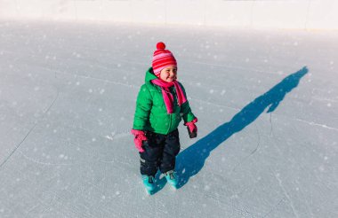 Mutlu küçük kız kışın paten kaymayı öğreniyor.