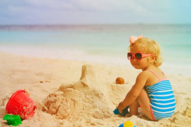 sevimli küçük kız sahilde kum ile oynamak