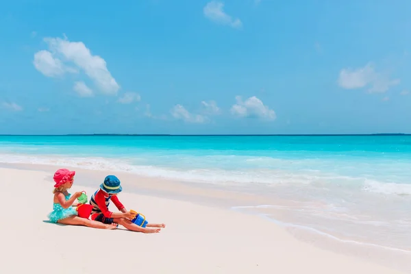 Niño y niña juegan con arena en la playa —  Fotos de Stock