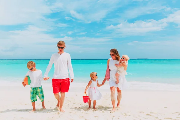 Familia feliz con tres niños a pie en la playa —  Fotos de Stock