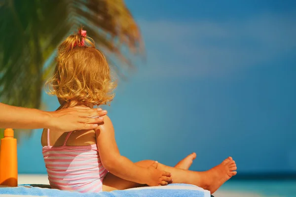Ochrana proti slunci na pláži - použití opalovací krém krém na rameni a dcera matka — Stock fotografie
